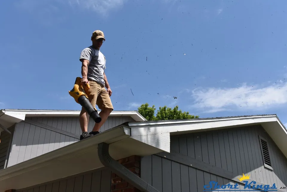 Standing on a roof ridge with a yellow blower against the blue sky