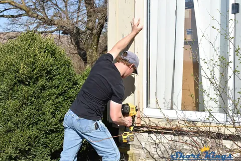 Nailing new wood trim beside a window
